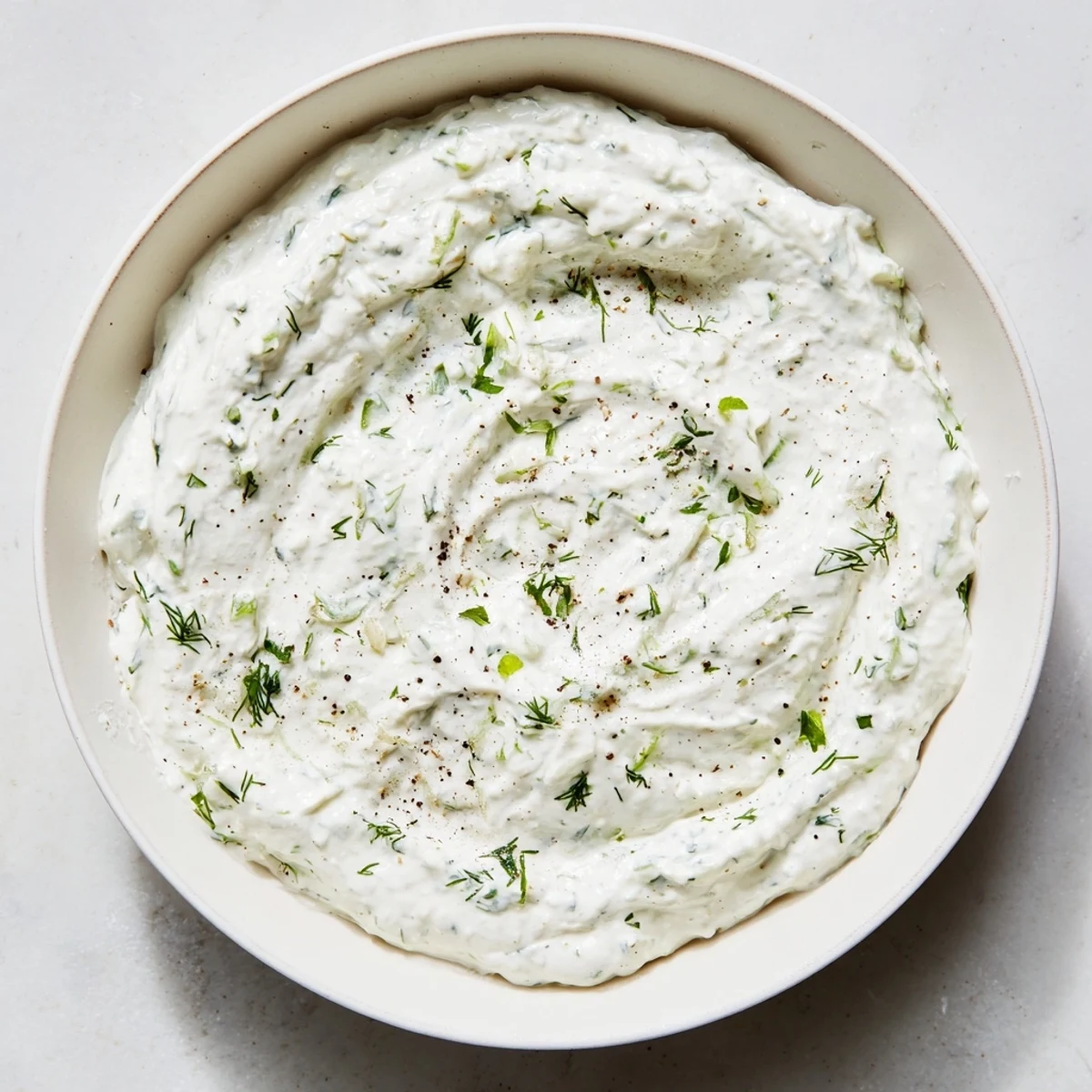 A bowl of homemade Greek Yogurt Ranch Dip, perfectly thick and ready for a party with fresh veggies.