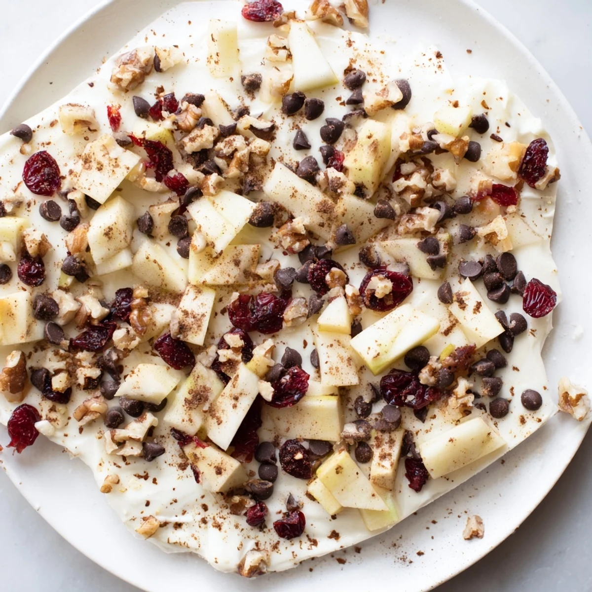 Frozen Apple Cinnamon Yogurt Bark, swirled with apples and nuts, ready for a refreshing treat.