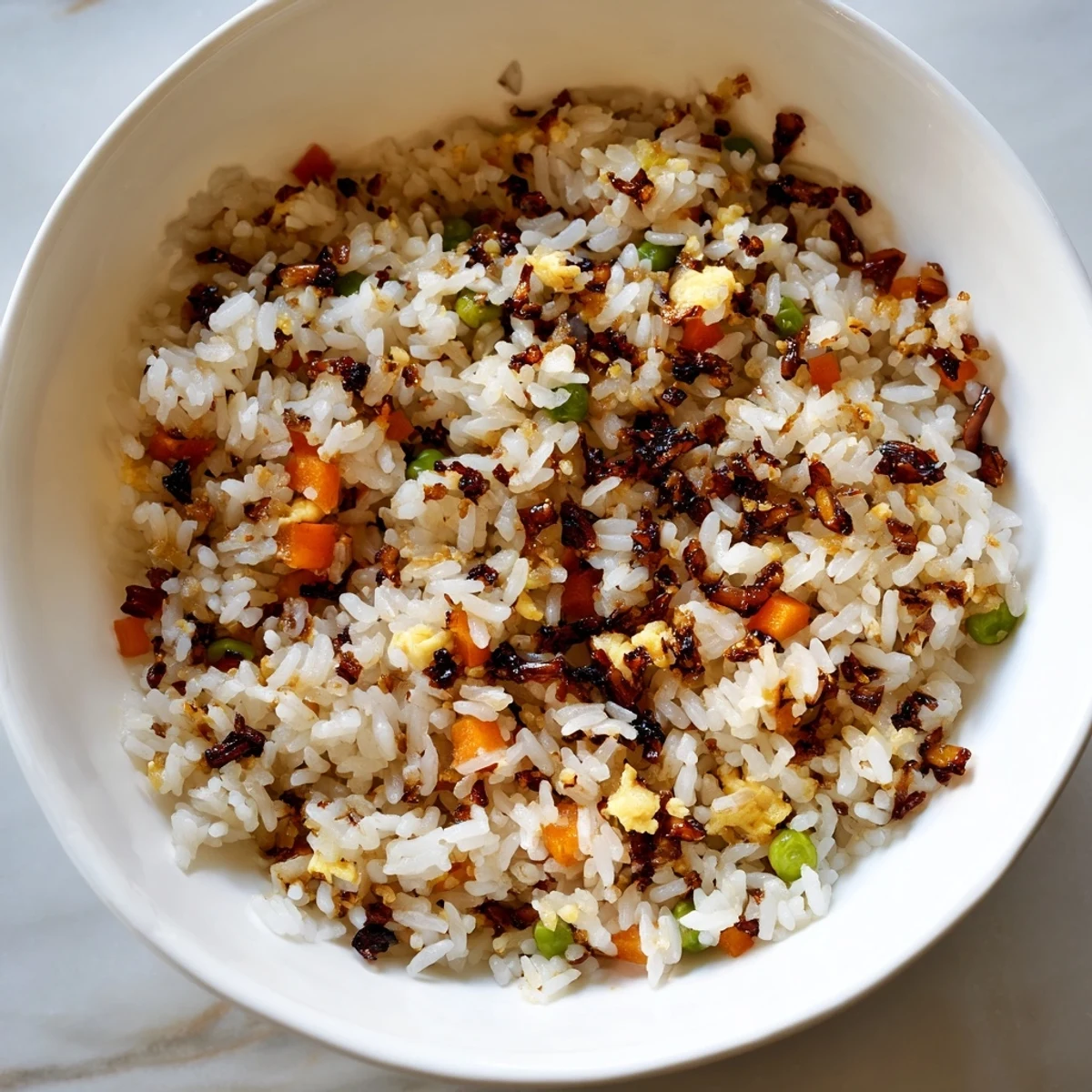 A vibrant bowl of Black Garlic Fried Rice topped with sliced scallions and scrambled egg, ready to be served as a main dish.