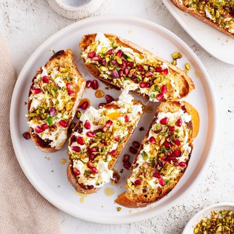 Toasted baguette rounds topped with creamy goat cheese and bright pomegranate seeds complete these Festive Crostini.
