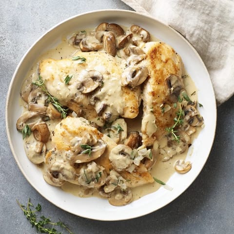Golden-brown skillet-seared chicken breast, glistening with rich mushroom cream sauce, perfect for dinner.
