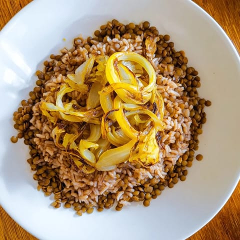 Golden caramelized onions topping a warm bowl of Lebanese Mjadra with perfectly cooked lentils and rice.