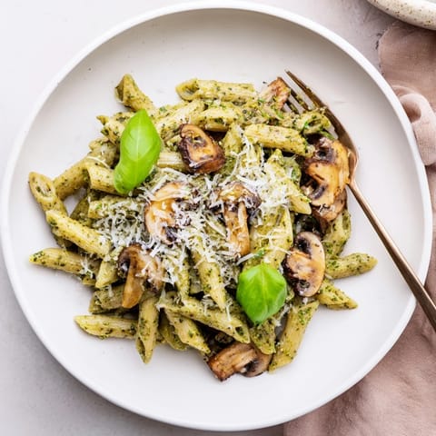 Sautéed cremini mushrooms tossed with al dente pasta in a rich, homemade basil pesto cream sauce for a comforting meal.