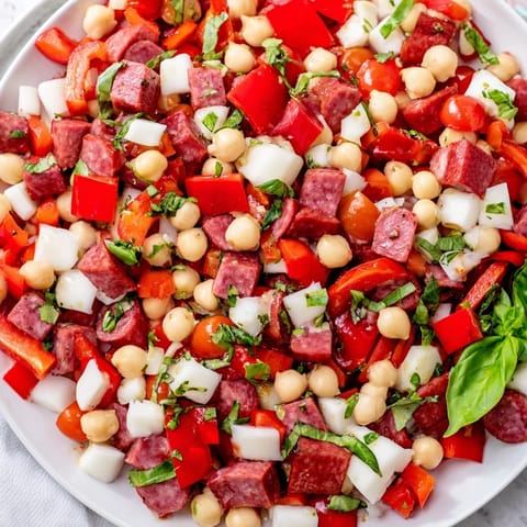 Close-up of a bowl of Crunchy Antipasto Chopped Salad with colorful peppers, olives, and fresh herbs.