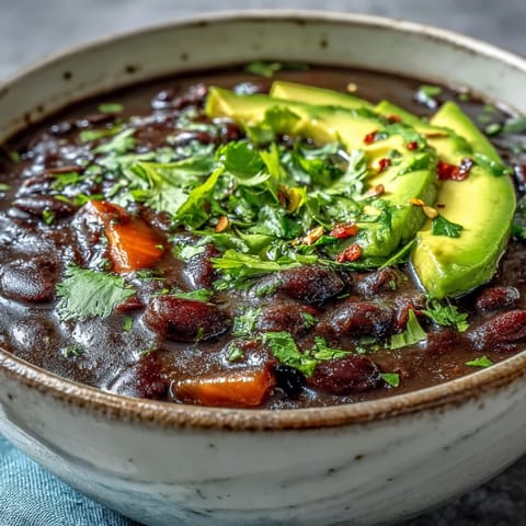 A pot of simmering Black Bean Soup with visible spices and diced vegetables, ready to be served for a cozy family dinner.
