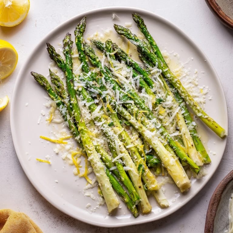 Close-up of roasted asparagus glistening with olive oil and Parmesan cheese, ready to serve.