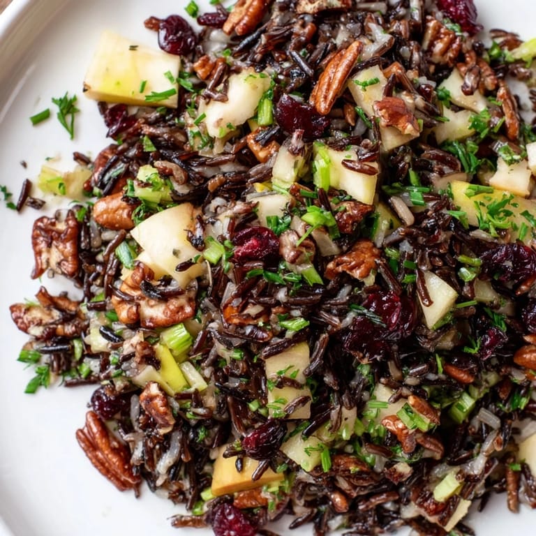 Spooning a serving of Wild Rice Harvest Salad onto a plate, highlighting the nutty grains, bright cranberries, and glistening dressing.