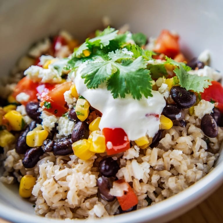 Close-up of a Brown Rice Burrito Bowl with brown rice, beans, peppers, corn, tomatoes, cheese, and fresh cilantro garnish.