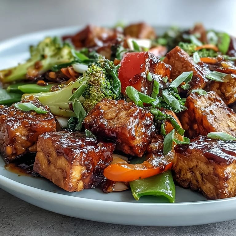 Sizzling Vegetable Tempeh Stir-Fry in a wok, featuring crisp sugar snap peas and tender broccoli florets glistening with savory glaze.